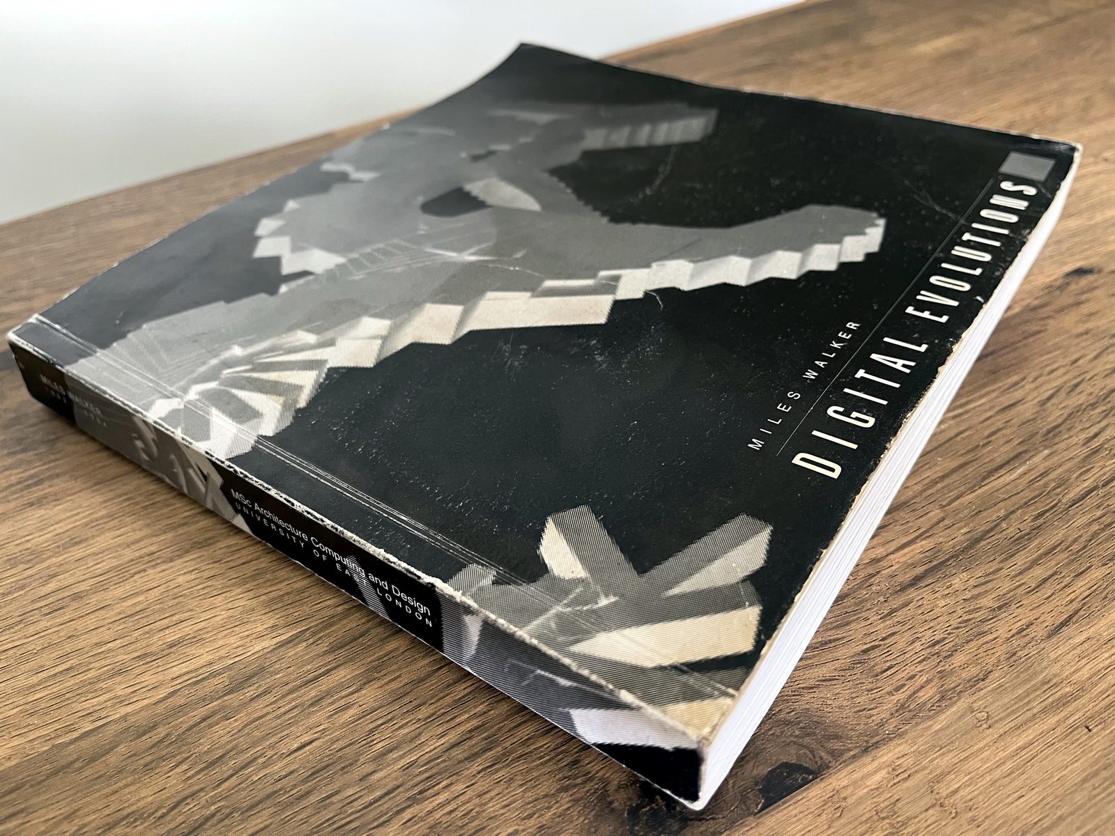 The 1994 MSc thesis Digital Evolutions, closed on a wooden table, its spine reading Miles Walker, MSc Architecture Computing and Design, University of East London.